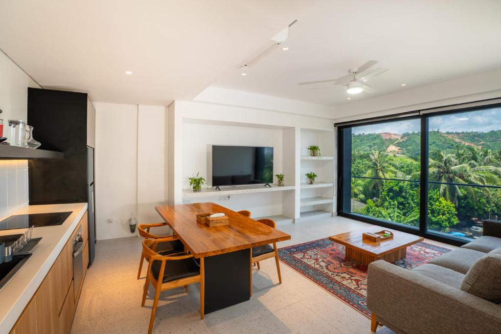 a kitchen and living room with a table and a large window at CASA MIA - Luxury Apartments Central Kuta in Kuta Lombok