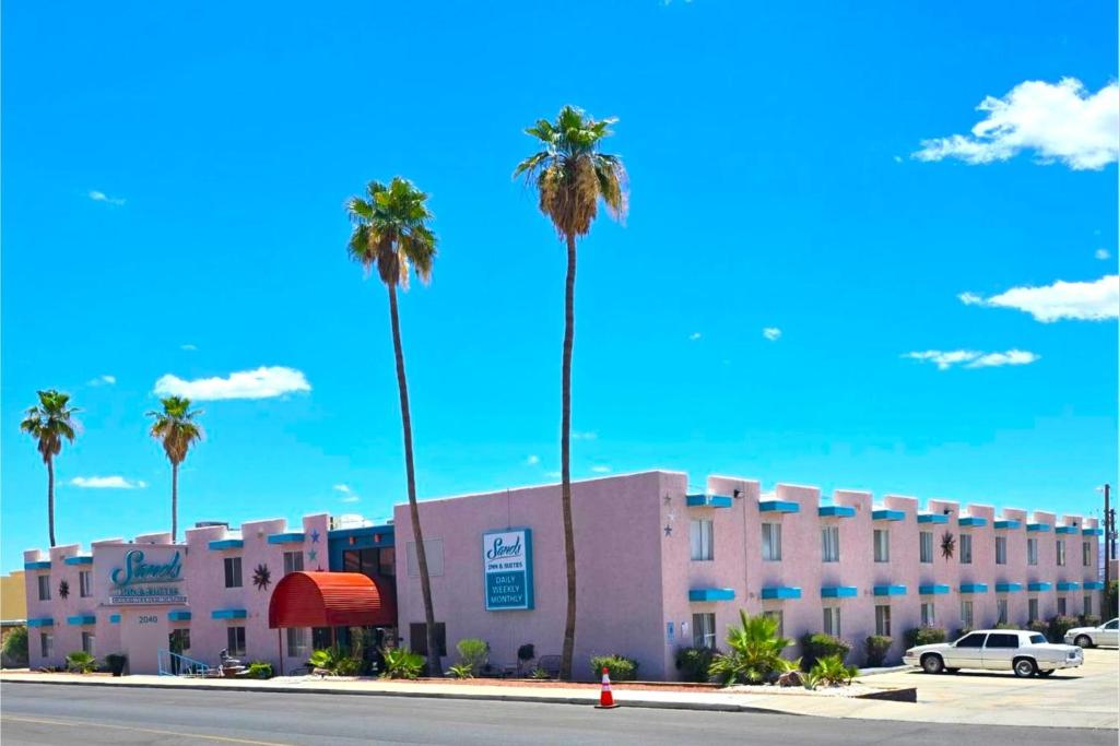 a building with palm trees in front of a street at Sands Inn & Suites Lake Havasu City in Lake Havasu City