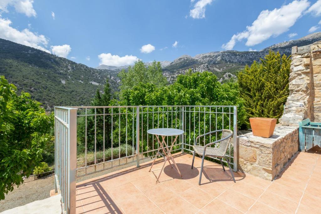 a balcony with a table and chairs and mountains at Akros Oreon, Omalos Studio in Káto Sími