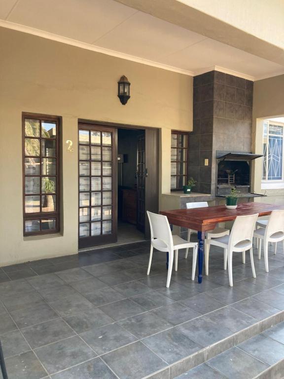 a kitchen with a wooden table and white chairs at 51 on Parfitt in Bloemfontein