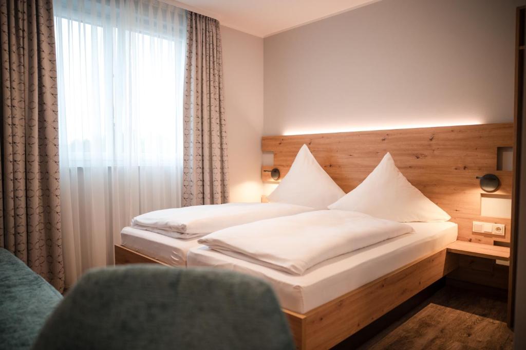 a bedroom with a bed and a window and a chair at Gasthaus Stroh in Buchholz