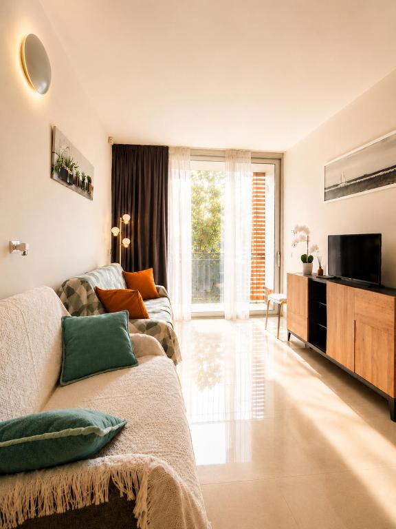 a living room with a couch and a television at Apartment Mare45 - 10 minutes walk from the beach with one private ombrella and three sun-beds in Eraclea Mare