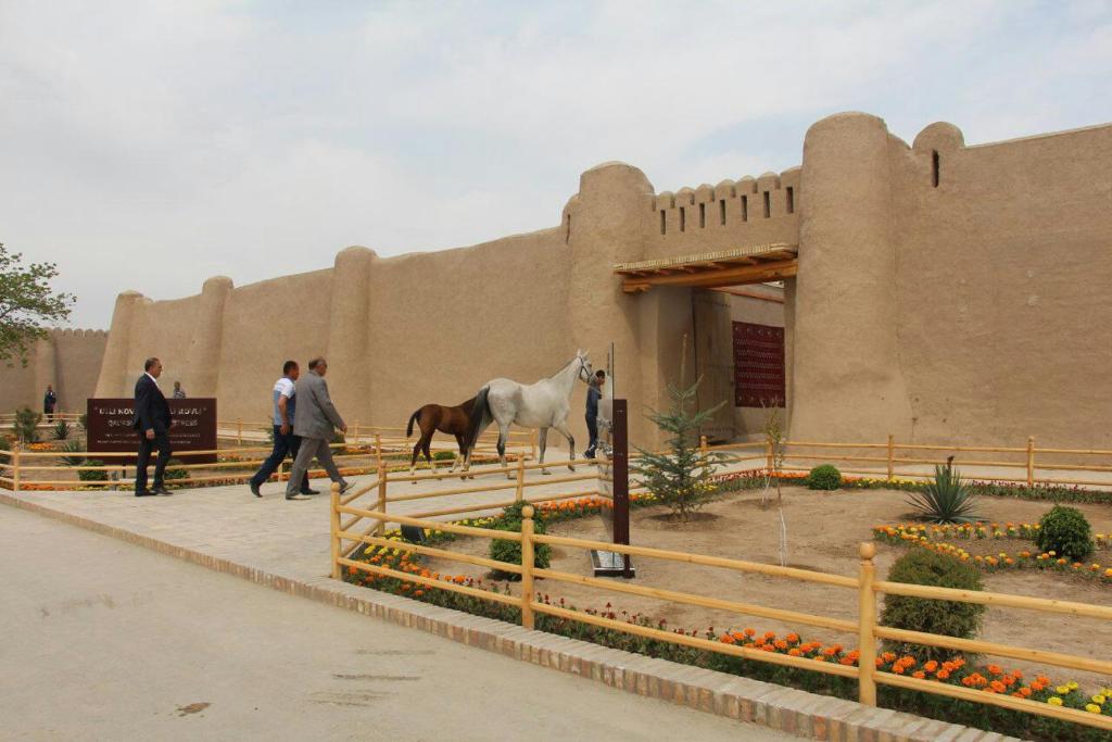 a man walking a horse in front of a building at TURKMAN's PALACE in Urganch