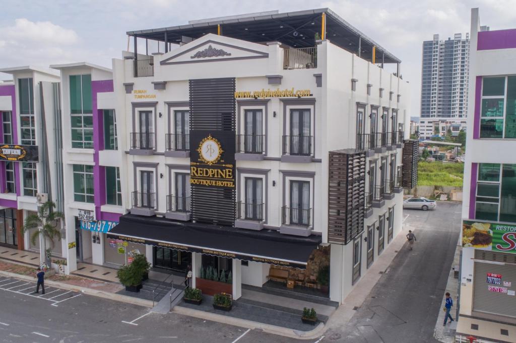 a large white building with a sign on it at Redpine Hotel in Skudai