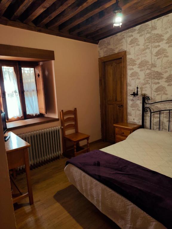 a bedroom with a bed and a desk and a chair at La Posada de San Martin in San Martín del Castañar