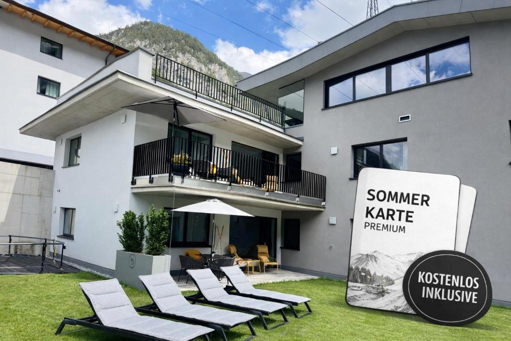 a house with chairs and a sign in front of it at Apart Galeon in Pettneu am Arlberg