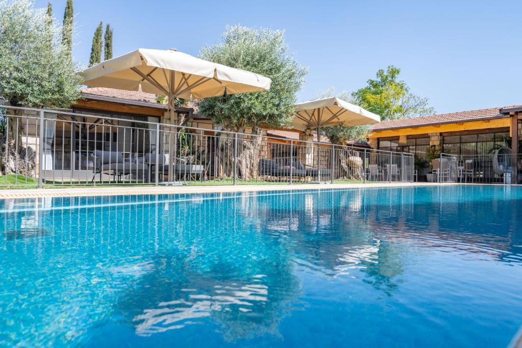 a large blue swimming pool with an umbrella at וילה ואמוס - Villa vamos - וילה מדהימה עם בריכה פרטית וג'קוזי in Rosh Pinna