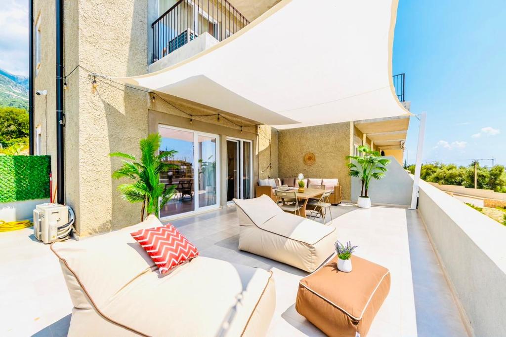 an outdoor living room with white furniture on a balcony at Boho Mar Drymadhes by PS in Dhërmi