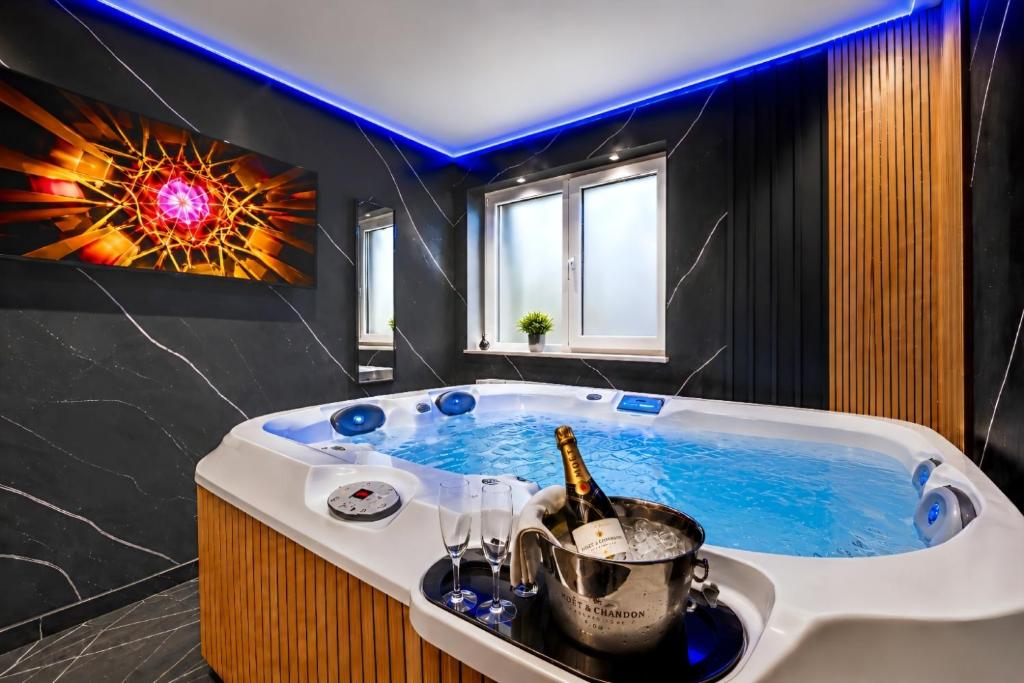 a bathroom with a tub with a bottle of champagne at Luxor - Private Jacuzzi Boulevard Suites in Sibiu