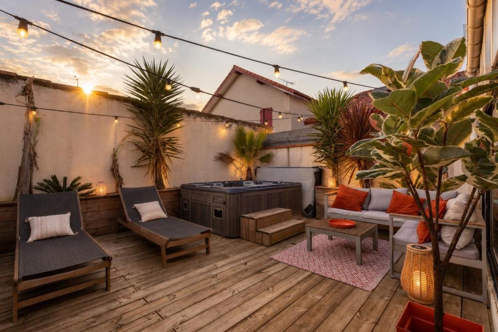 an outdoor patio with a grill and chairs and plants at Villa NOVA in Capbreton
