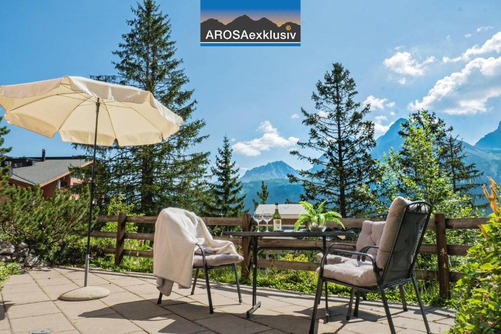 a patio with a table and chairs and an umbrella at Haus Belvédère in Arosa