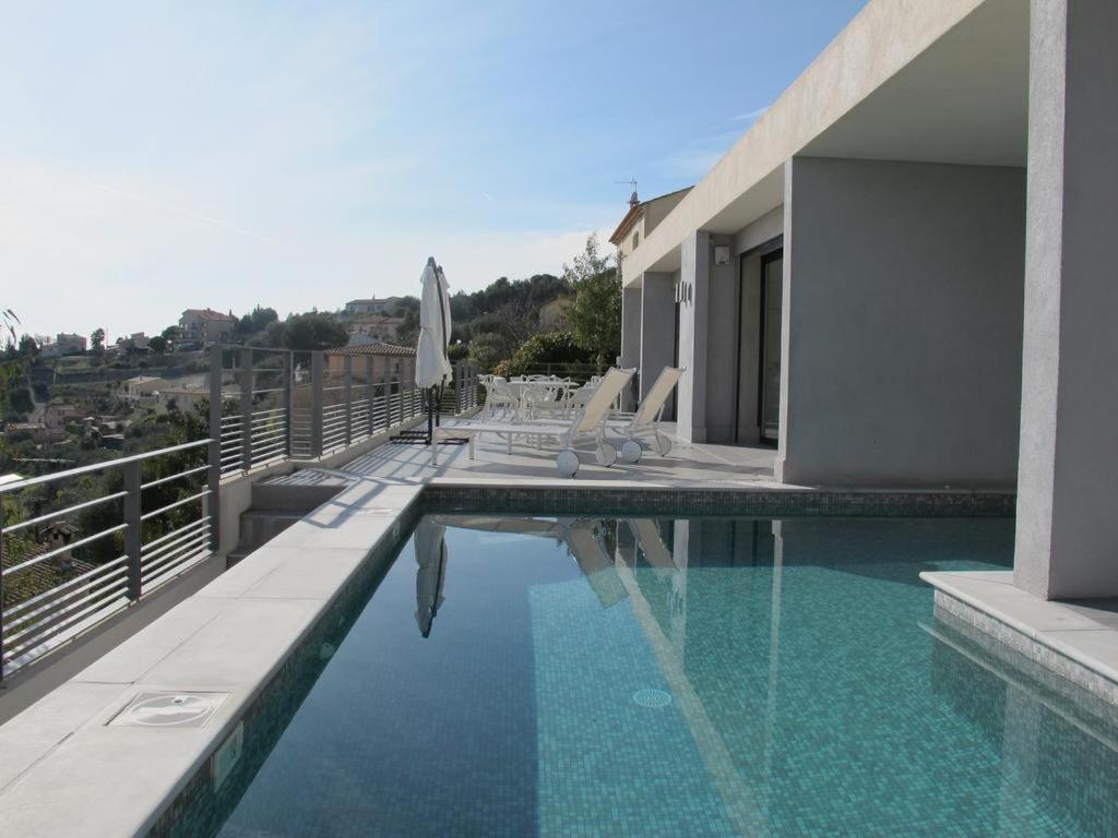 a swimming pool with chairs and an umbrella on a building at LOCATION VACANCES NICE - Villa 5* Nice St Pancrace in Nice
