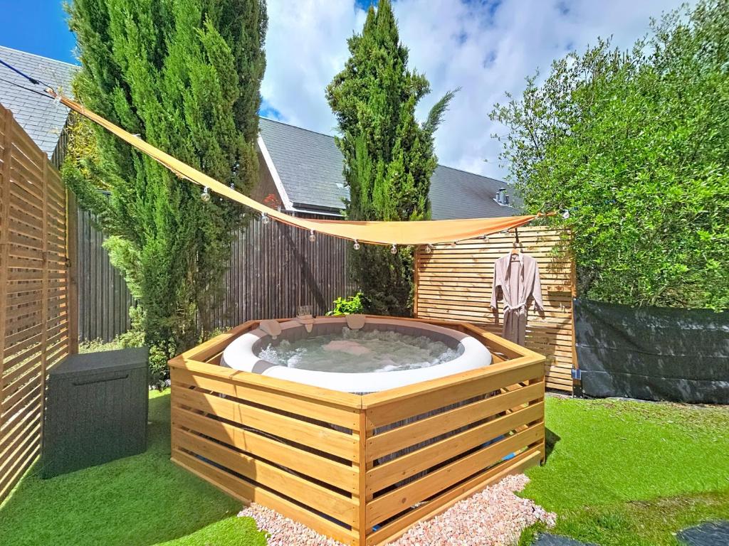 a hot tub in a garden with a hammock at Maisonnette d'architecte face nature, 15min de Tours in Charentilly