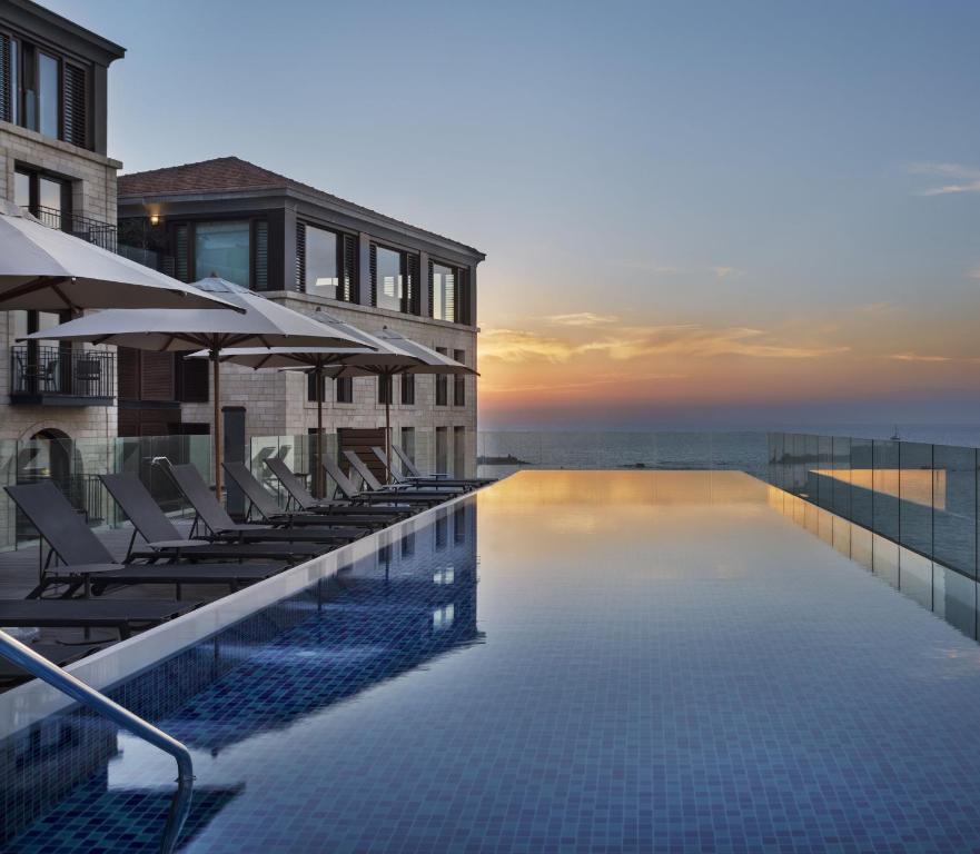 a hotel swimming pool with chairs and the ocean at The Setai Tel Aviv, a Member of the leading hotels of the world in Tel Aviv