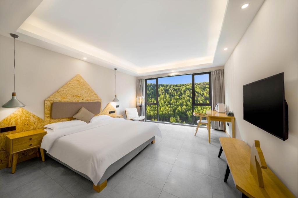 a bedroom with a bed and a desk and a tv at Jianshanxi Designer Hotel in Mount Siguniang