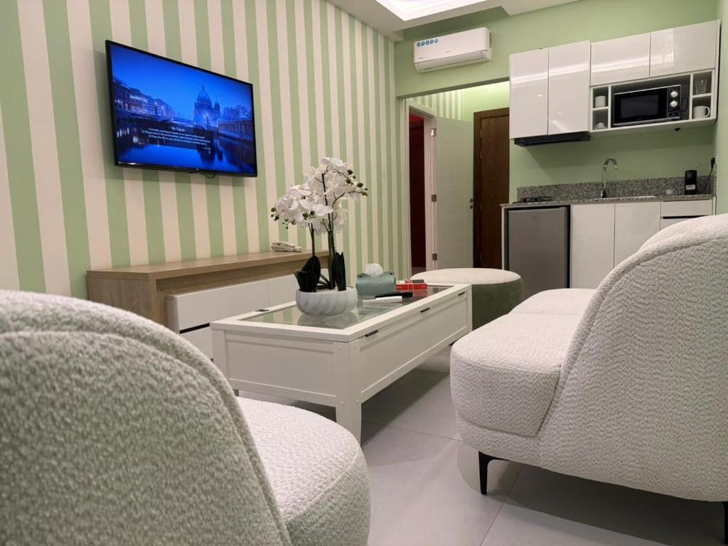a living room with two chairs and a tv on the wall at Shade Hotel Beirut in Beirut