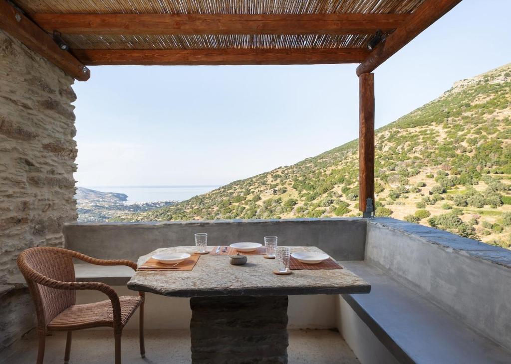 a table and chairs on a balcony with a view at Falcon Eyes- Panoramic stone house in Andros