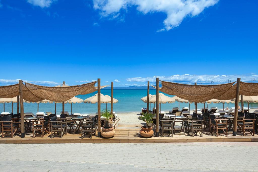 a restaurant on the beach with chairs and umbrellas at Adriana beach in Pefkochori