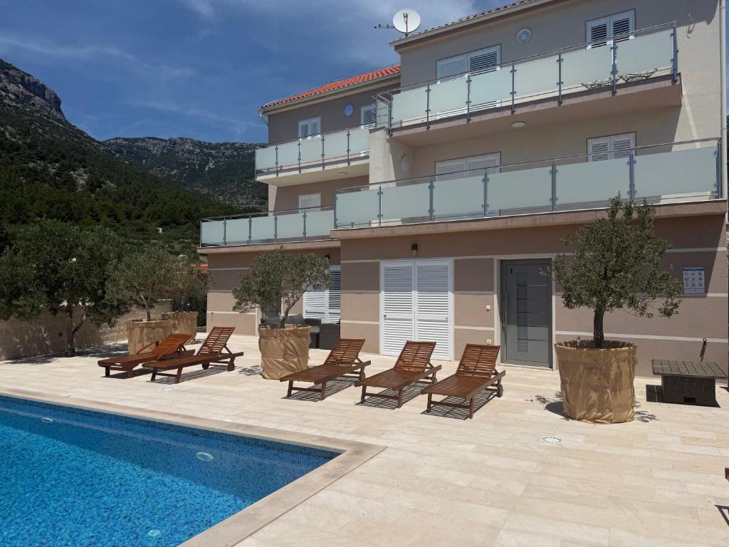 a building with chairs and a swimming pool at Villa Nikola - pool side apartments in Bol