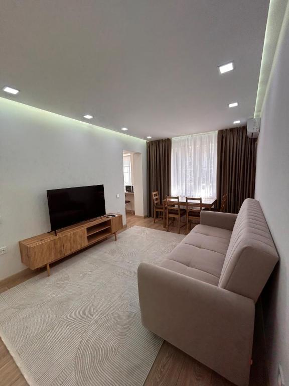 a living room with a couch and a flat screen tv at Three rooms on Arbat in Shymkent