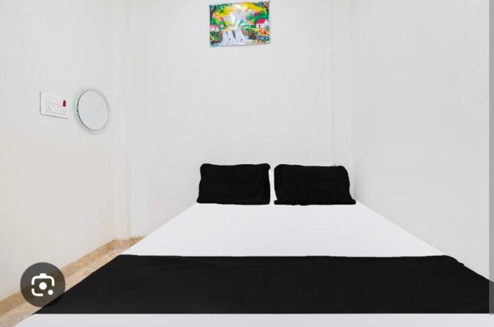 a white bed with black pillows in a room at Trip Kashi Guest House in Varanasi