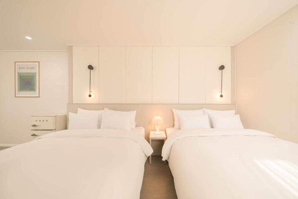 two beds in a room with white walls at No25 Hotel Chuncheon Cityhall in Chuncheon