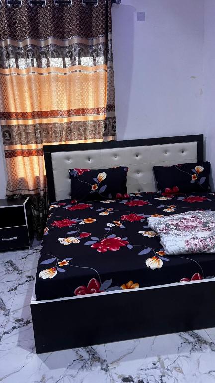 a bed with a black comforter with flowers on it at Bright Moon Hotel limited in Enugu