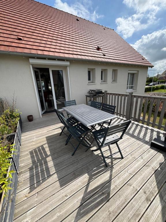 a wooden deck with a table and chairs on it at La Maison des phares in Lion-sur-Mer
