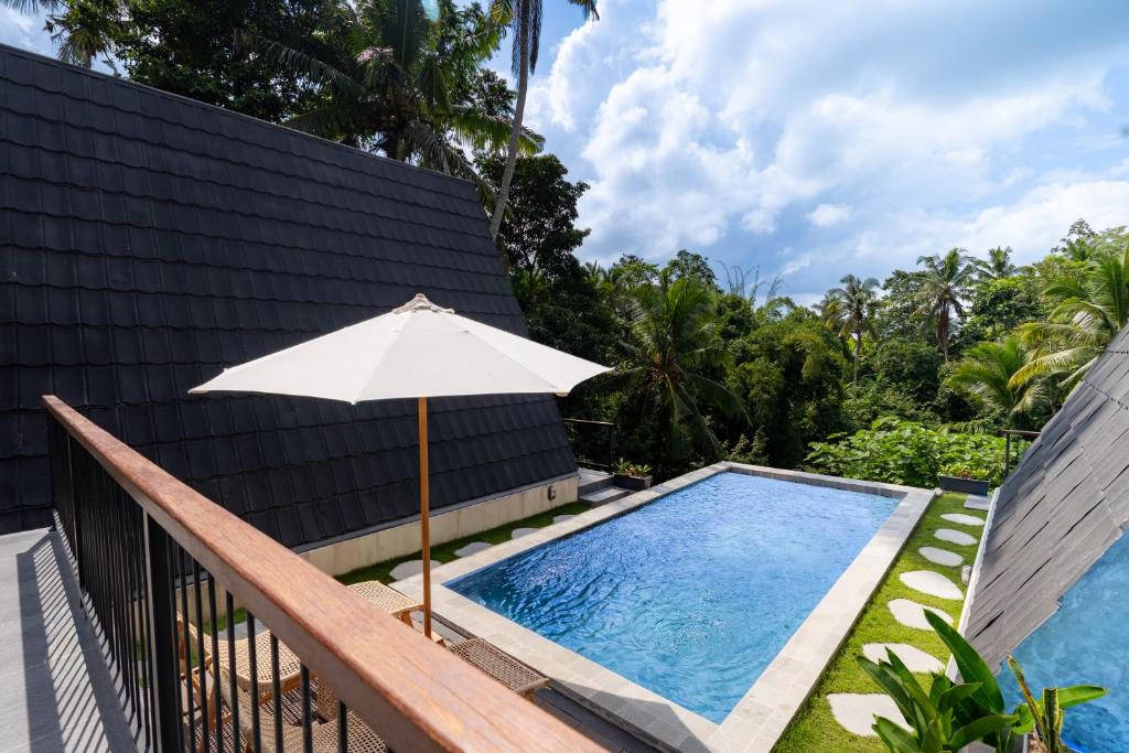an umbrella sitting next to a swimming pool at Green Tara Valley Ubud by Betterplace in Ubud