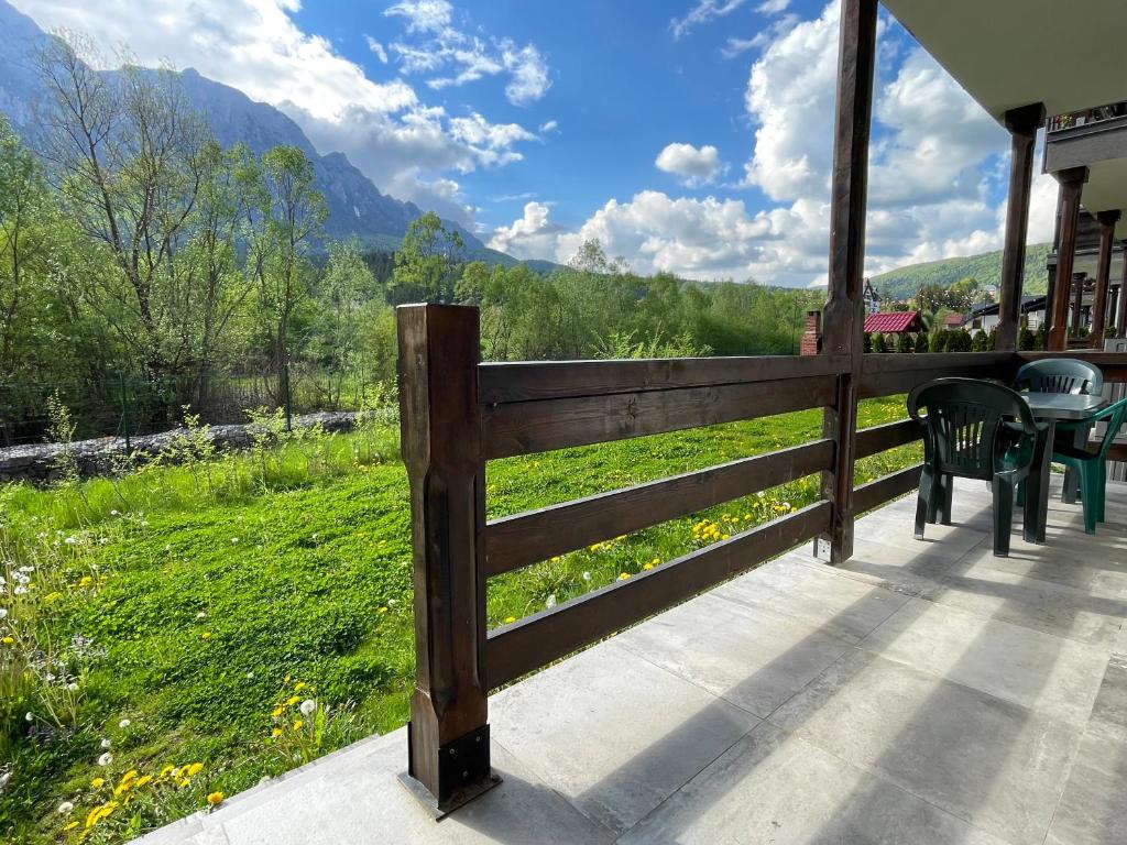 a porch with a fence and a table and chairs at Cozy Riverfront Apartments with garden and mountain view in Buşteni