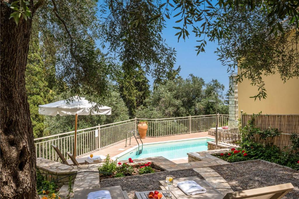 a swimming pool with a table and an umbrella at Villas Muscalas by Konnect, 200m from the Beach in Lákka