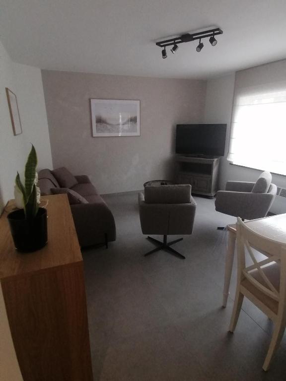 a living room with a couch and chairs and a tv at Marisol in Bredene