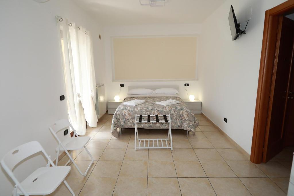 a bedroom with a bed and two white chairs at Introdacqua Holidays in Sulmona