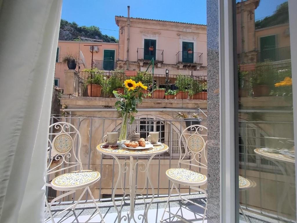 a table with a vase of flowers on a balcony at La Chicca nel Barocco - Modica Centro - Indipendente in Modica