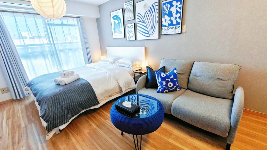 a bedroom with a bed next to a couch at Sidihome 365 Apartment in Osaka