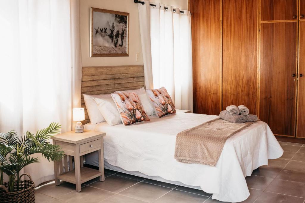 a bedroom with a white bed with a wooden wall at Lekkerbly Self Catering in Pofadder