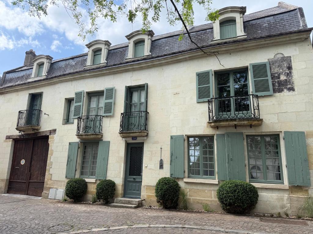 an old house with green shutters on a street at Maison Romy in Chinon