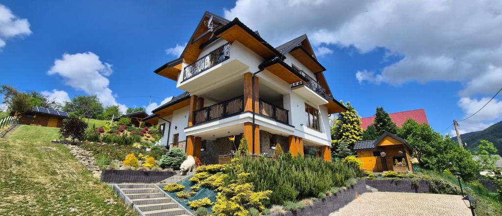 a house on a hill with flowers in front of it at Willa Golasówka in Muszyna