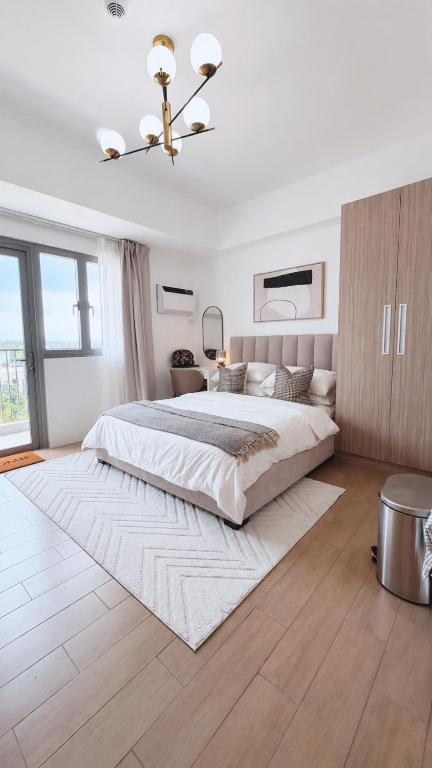 a white bedroom with a large bed and a chandelier at studio MA-DE cozy Bacolod City in Bacolod