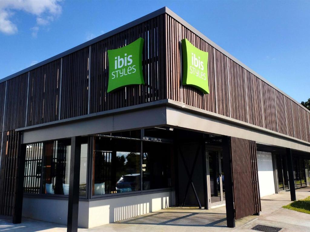 a building with two green signs on the side of it at IBIS STYLES Rouen Parc Expos Zenith in Saint-Étienne-du-Rouvray