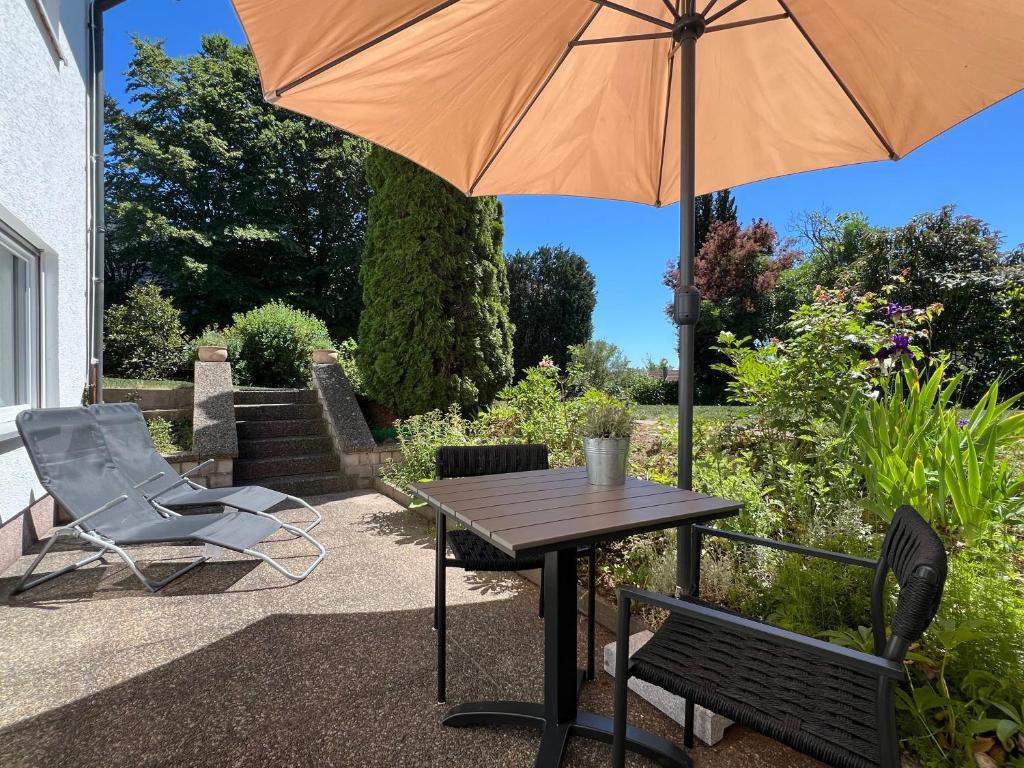 a table and chairs and an umbrella on a patio at Kappelblick Apartment ohne Küche - mehr als nur ein Doppelzimmer in Burgthann