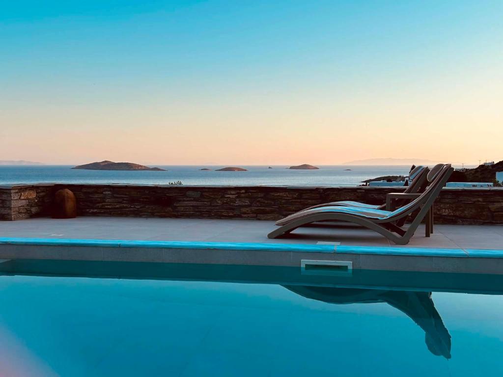 a pair of chairs sitting on the edge of a swimming pool at ELIA PRIVILEGED SUITES Andros ΑΝΔΡΟΣ in Andros