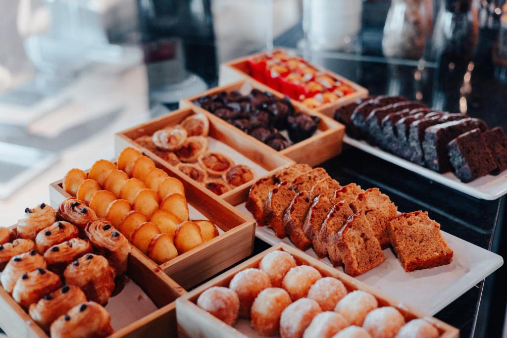 A pastry display with assorted sweet breakfast items arranged in trays and wooden boxes.