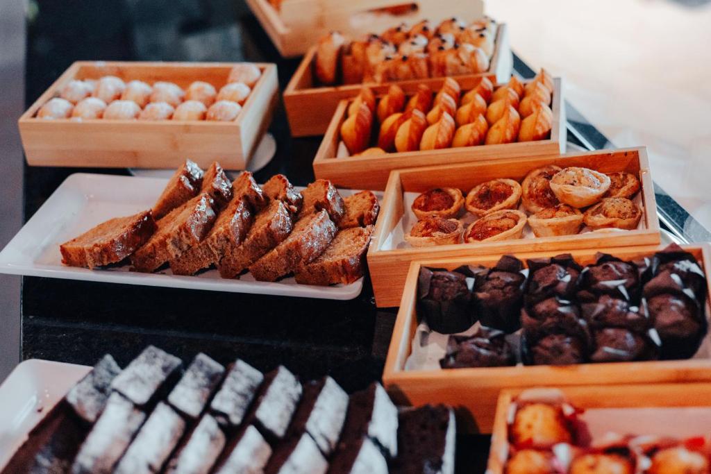 A close-up breakfast spread of pastries and sliced cakes in wooden trays.