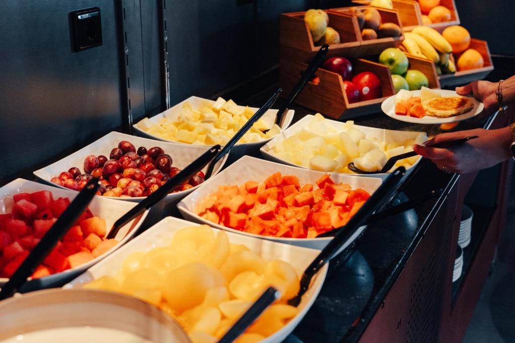 A fruit buffet with cut melon, watermelon, papaya, grapes and whole fruit.