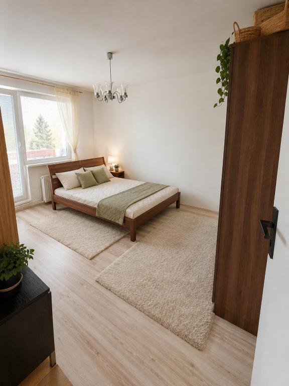 a bedroom with a bed and a large window at Apartman Anna in Závada