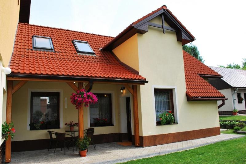 a house with an orange roof with a table and chairs at Chalupa Evka in Terchová