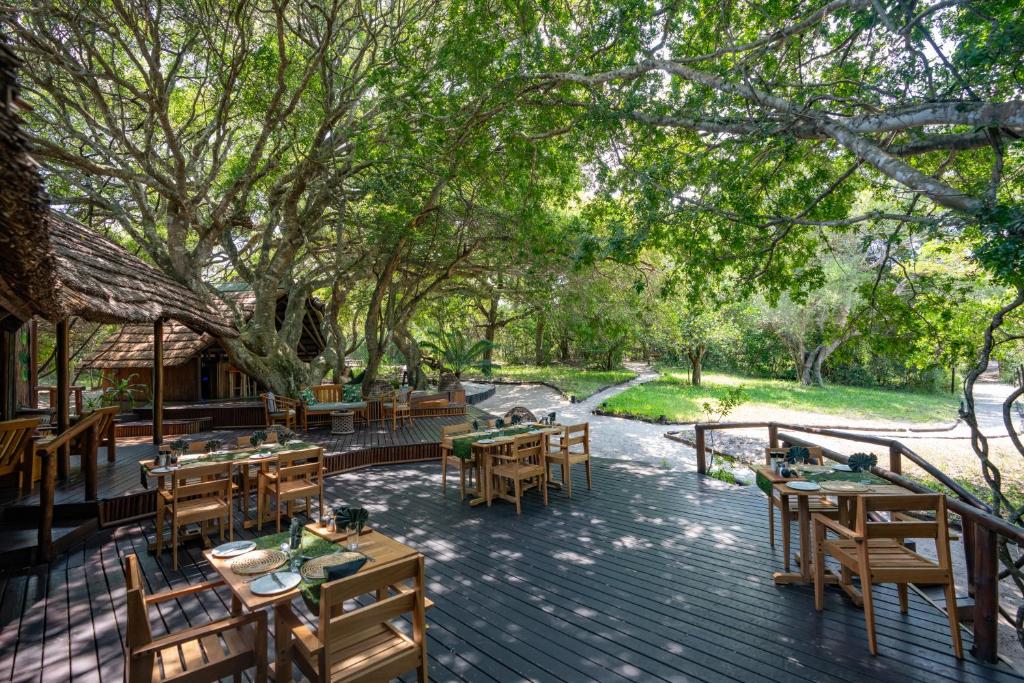 an outdoor patio with tables and chairs and trees at Kosi Forest Lodge in Manguzi