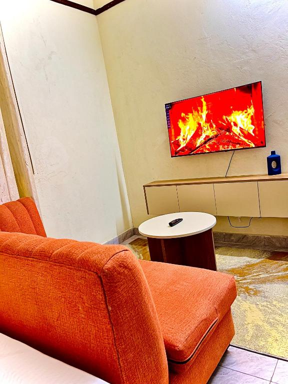 a living room with a couch and a tv on a wall at Studio Kilifi -Pendoraha Homes in Kilifi