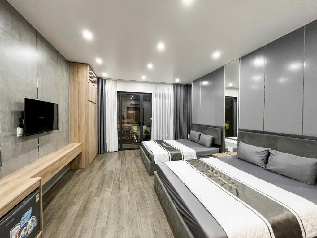 a hotel room with two beds and a tv at Lamer Hostel in Cat Ba